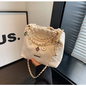 Détail d'un sac seau matelassé crème avec breloques cœur colorées et chaîne dorée