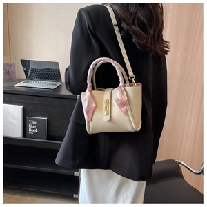 Detail of off-white bucket bag with printed silk scarf handle and gold metallic buckle