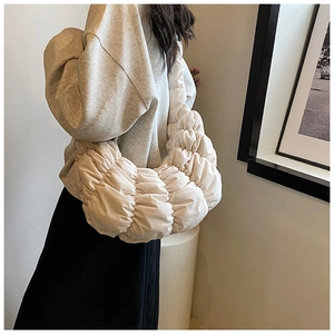 Detail einer beigen Plissee-Croissant-Tasche mit flauschiger Textur und weichem Nylon