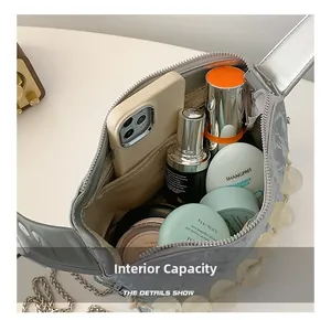 Detail van de binnenruimte van de zilveren schoudertas met mobiele telefoon en cosmetica