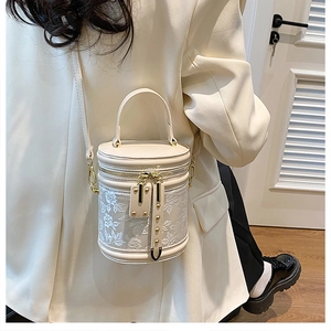 Detailed view of cream bucket bag with lace embroidery worn with a beige blazer