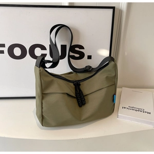 Detail of army green nylon messenger bag with black adjustable strap and cord pullers