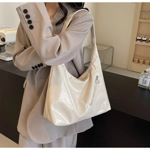 Chic cream oversized tote bag in glossy finish shown on model in a modern urban setting