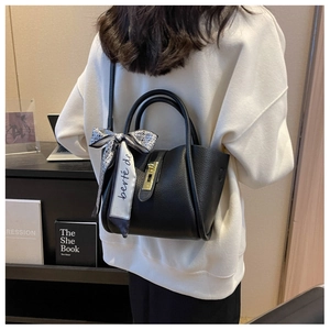 Detail of black lychee grain bucket bag with metal lock and patterned scarf