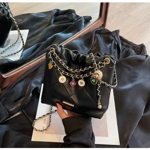 Vue détaillée du sac seau en cuir matelassé noir avec chaîne dorée et breloques