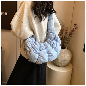 Hellblaue gesteppte Croissant-Tasche mit Faltenstruktur als Umhängetasche am Model