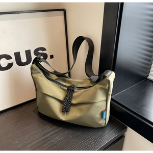 Close-up of army green crossbody bag with adjustable wide strap and knotted zipper detail