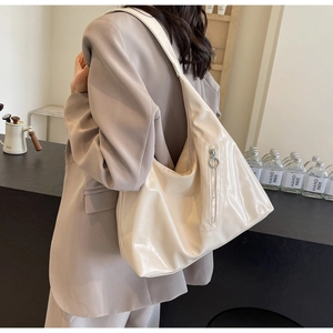 Detail of soft cream hobo tote bag with vertical zipper pocket and round metal puller