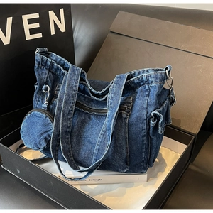 Dettaglio della trama della borsa tote in denim blu con cerniera argento e tasche laterali