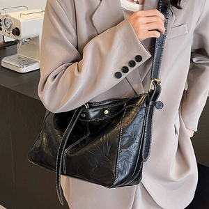 Black leather tote bag with white contrast stitching and adjustable strap for women