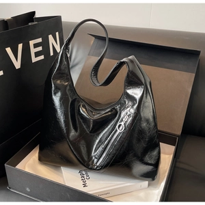 Close-up of a black hobo bag in a luxury gift box with white dust bag and subtle lighting
