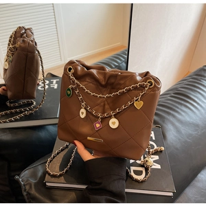 Détail du sac en cuir matelassé marron avec pendentifs en cœur et bandoulière dorée