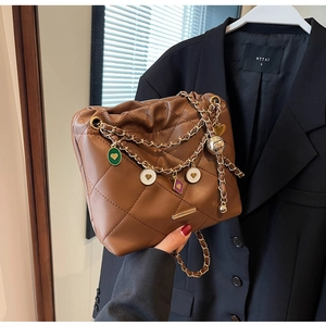 Détail du sac seau marron foncé en similicuir matelassé avec chaîne et breloques de mode