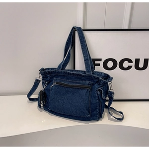 Dettaglio borsa tote in denim blu scuro con tasca a zip e mini borsellino attaccato