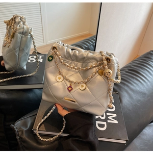Détail du sac seau matelassé argenté avec chaîne dorée et breloques de cœur en émail