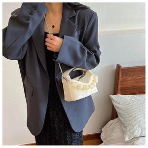 Detail van de crème crossbodytas met rond kralenhandvat en zilveren kettingriem