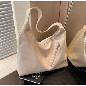 Macro detail of creamy white PU leather hobo bag with glossy texture and ring zipper
