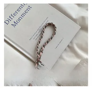 Détail de la chaîne argentée entrelacée de cuir rose sur un sac en soie brodée