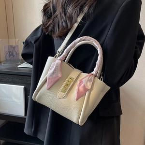 Chic beige lychee leather bucket bag with golden lock and decorative silk scarf handle