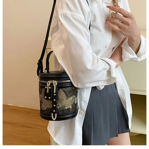 Close-up of black bucket bag featuring intricate gold butterfly embroidery and dual zippers