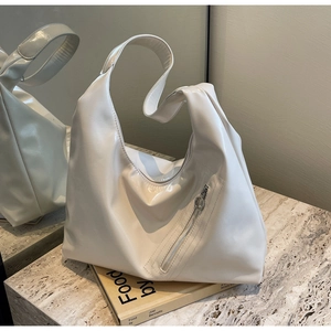 Detailed close-up of cream glossy hobo bag with silver zipper on marble surface