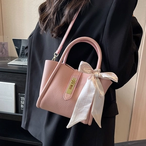 Pink lychee textured bucket bag with decorative scarf and gold clasp shown on model