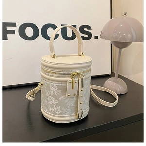 Detail of floral embroidery on beige bucket bag with gold hardware and top handle