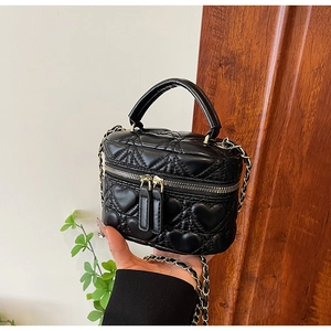 Detailed close-up of heart quilted mini chain box bag with gold double zippers