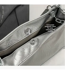 Detail der silbernen Metallic-Tasche mit Magnetverschluss und Fischgräten-Innenfutter