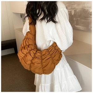 Detailansicht der karamellbraunen Croissant-Tasche mit Falten an der Schulter des Models