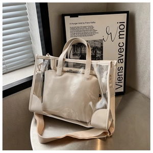 Detail view of transparent PVC tote with cream inner pouch and wide textile shoulder strap
