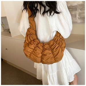 Detail der karamellbraunen Falten-Croissant-Tasche mit weißem Vintage-Puffärmelkleid