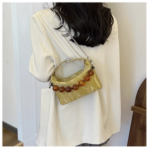 Chique beige getextureerde crossbodytas met barnsteen kralen en zilveren ketting op model