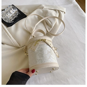 Detail of embroidered floral pattern and gold zippers on beige cylinder bucket bag