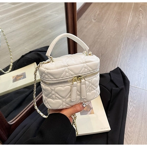 Close-up of white heart-quilted mini box bag with gold double zippers and chain strap