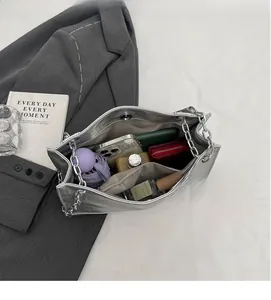 Geräumiges Innenleben der silbernen Metallik-Tasche mit Fächern und Kettenriemen
