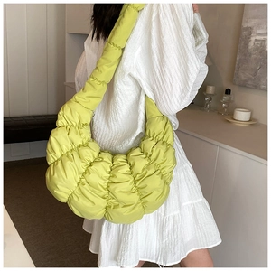 Detail der lindgrünen Croissant-Tasche mit weichem Faltenstoff auf weißem Kleid