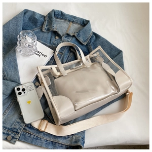 Detail of transparent PVC jelly tote with leather trim and inner pouch on denim fabric