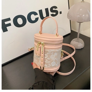 Detail of pink faux leather bucket bag with white floral lace and gold rivet accents