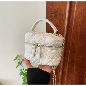 Detail of cream mini box bag with heart quilting and gold chain strap