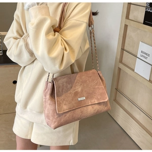 Detail der rosa Wildleder-Umhängetasche mit silbernem Logo und Metallkettenriemen