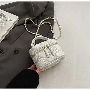 Detail showing white heart-quilted mini box bag with gold chain strap and dual zippers