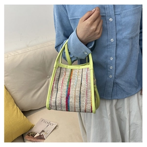 Detail einer bunt gestreiften Webhandtasche mit neongrünem Rand, von Modell gehalten