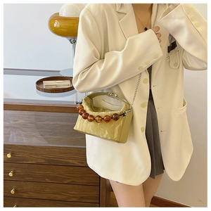 Detail van mosterdgele crossbodytas met amberkleurige kralen handgreep en zilveren ketting