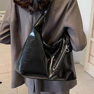 Chic black glossy leather tote bag for women with decorative zipper on brown suit model