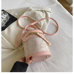Detailed macro view of pink cylinder bucket bag featuring delicate floral embroidery motifs