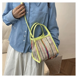 Foto de estilo de un bolso tipo cubo a rayas con borde amarillo neón en una modelo