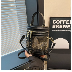 Detail of black leather bucket bag featuring elegant gold butterfly embroidery and strap