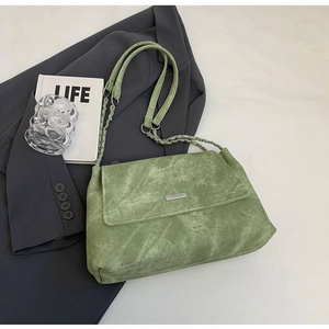 Detail der grünen strukturierten Tasche mit Metallkette und Marken-Namensschild