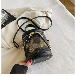 Detail of cylinder bucket bag featuring gold butterfly embroidery and smooth black leather